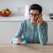 Stressed woman talking on the phone and looking at her credit card,